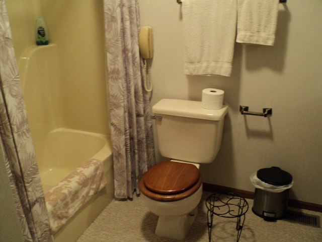 bathroom with shower / bath combo with shower curtain and toilet