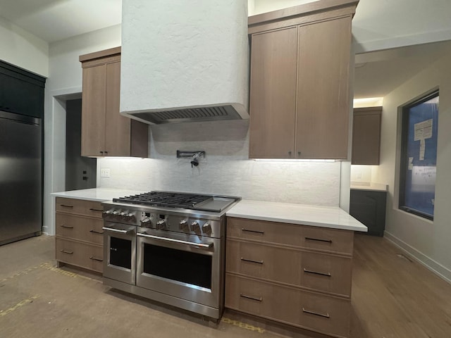 kitchen with range with two ovens, refrigerator, light countertops, and ventilation hood