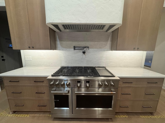 kitchen featuring ventilation hood, decorative backsplash, light stone counters, and double oven range