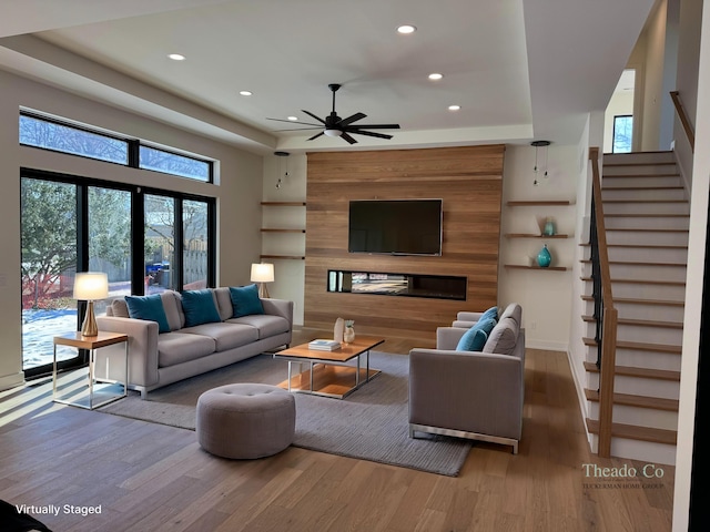 living area featuring stairs, a ceiling fan, wood finished floors, and recessed lighting