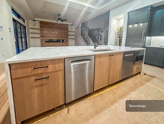 kitchen with tasteful backsplash, ceiling fan, appliances with stainless steel finishes, open floor plan, and a sink