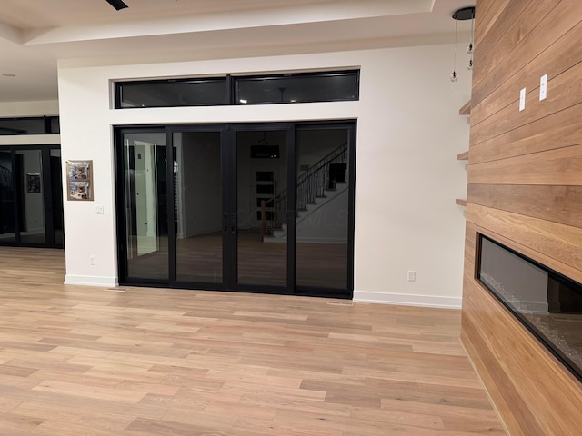 interior space with stairs, a tile fireplace, light wood-style flooring, and baseboards