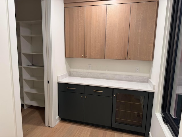 bar with beverage cooler and light wood-style floors