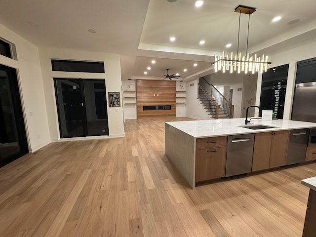 kitchen with open floor plan, a tile fireplace, light wood-type flooring, and a sink