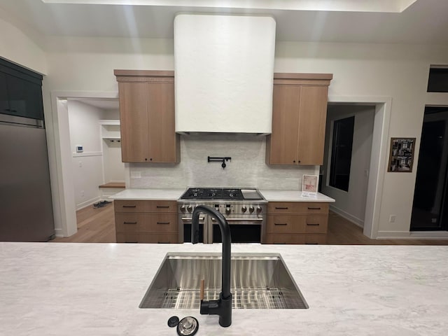 kitchen with high end stove, light countertops, a sink, and backsplash