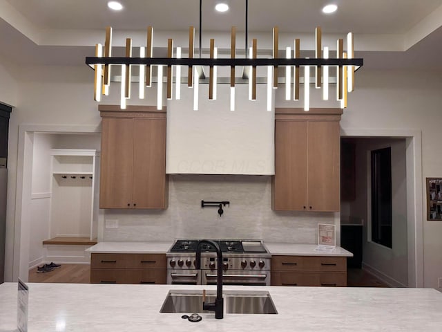 kitchen with a sink, double oven range, light countertops, and backsplash