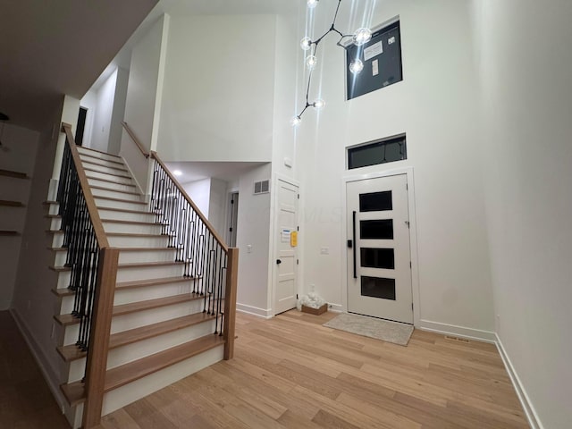 entryway featuring visible vents, stairway, baseboards, and wood finished floors