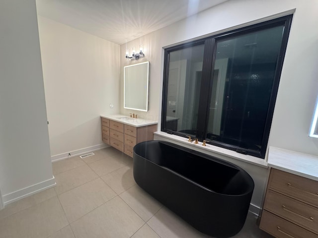 bathroom with visible vents, baseboards, a soaking tub, tile patterned floors, and vanity