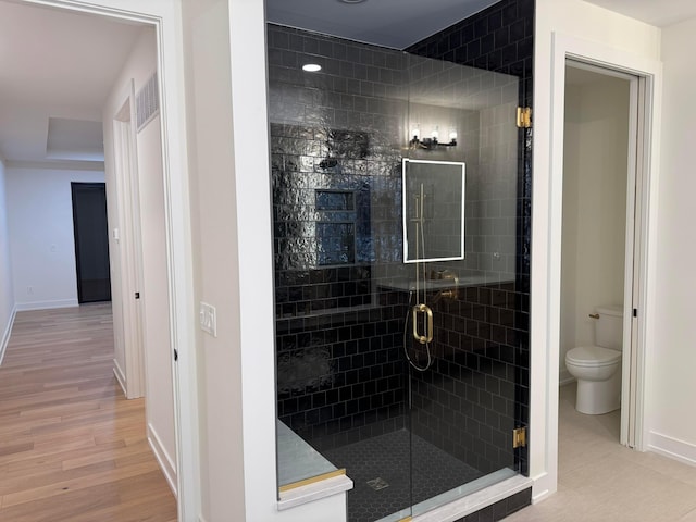 full bathroom featuring toilet, wood finished floors, visible vents, baseboards, and a stall shower