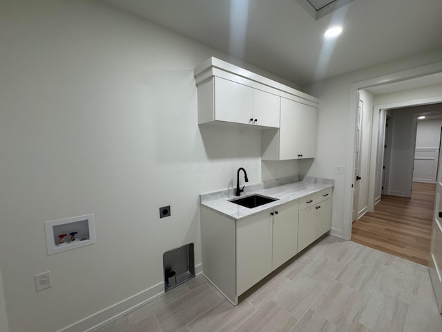 washroom featuring cabinet space, baseboards, hookup for an electric dryer, washer hookup, and a sink