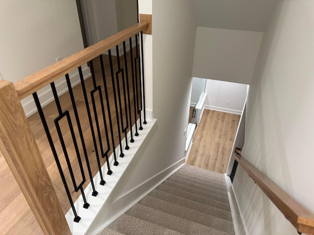 staircase featuring wood finished floors and baseboards