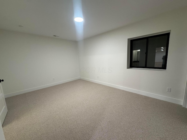 carpeted spare room featuring baseboards