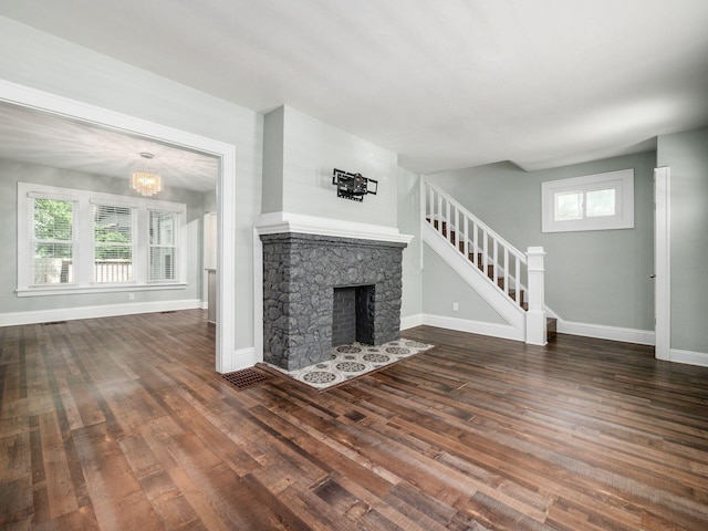 unfurnished living room featuring a healthy amount of sunlight, a fireplace, and dark wood-type flooring