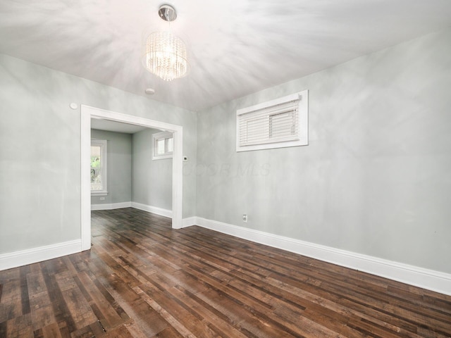 spare room with dark hardwood / wood-style floors and a chandelier