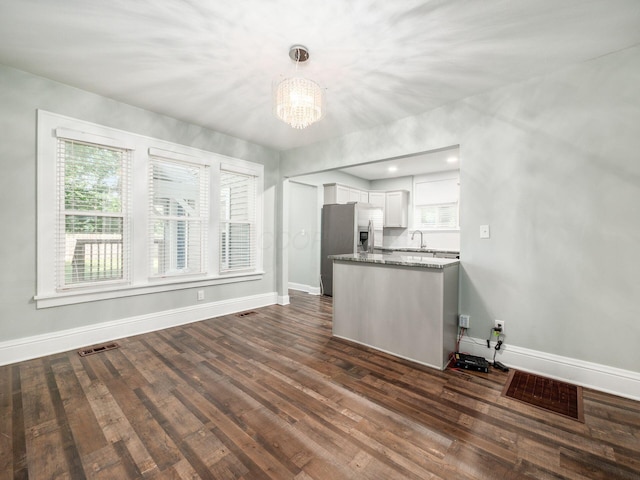 kitchen featuring pendant lighting, stainless steel fridge, dark hardwood / wood-style flooring, white cabinetry, and a chandelier