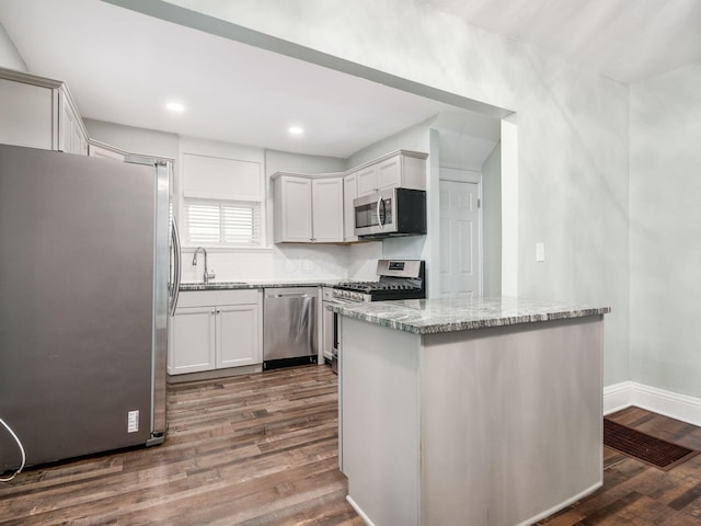 kitchen featuring white cabinetry, sink, dark wood-type flooring, light stone counters, and appliances with stainless steel finishes