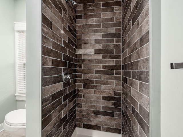 bathroom featuring a tile shower and toilet