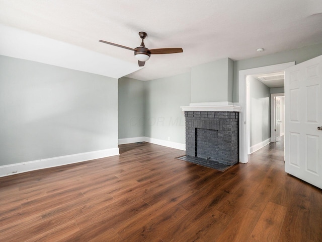 unfurnished living room featuring ceiling fan, dark wood-type flooring, and a brick fireplace