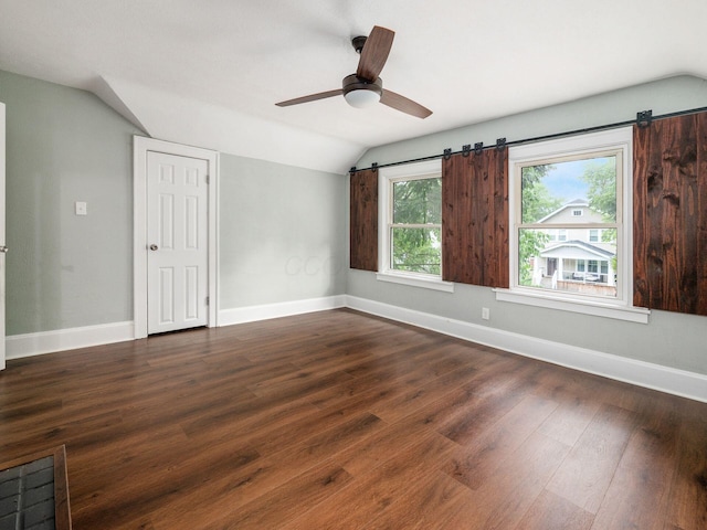 unfurnished room with a barn door, dark wood-type flooring, ceiling fan, and lofted ceiling