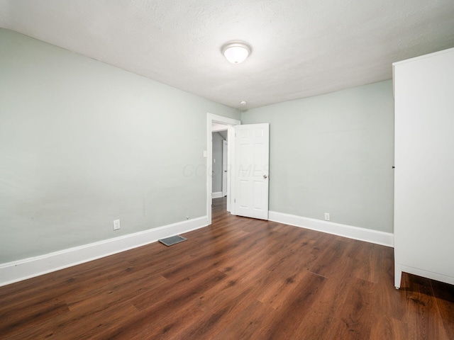 spare room with dark hardwood / wood-style floors and a textured ceiling