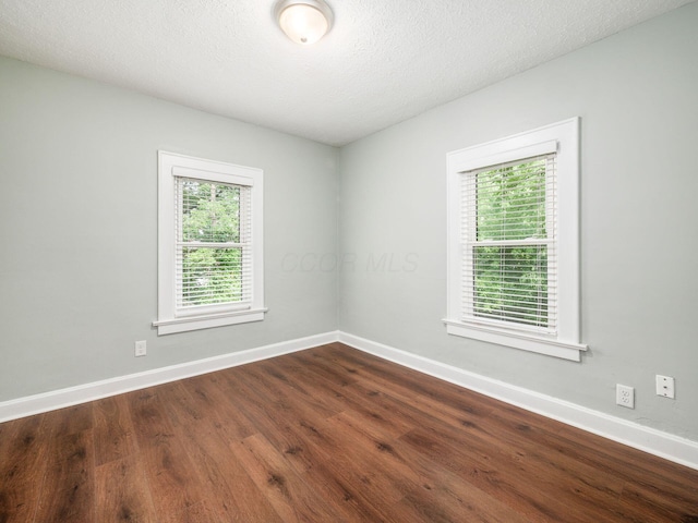 empty room with wood-type flooring and a textured ceiling