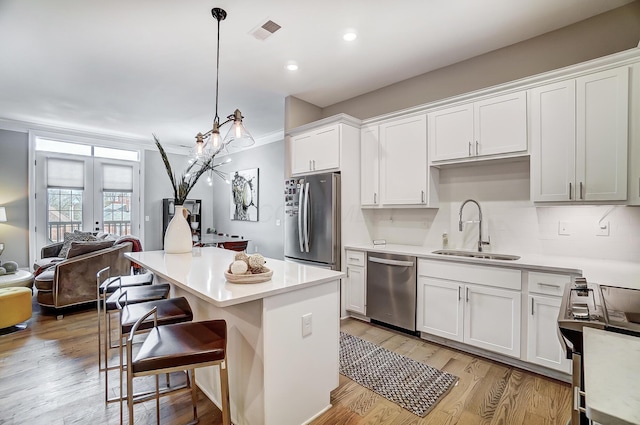 kitchen with white cabinetry, sink, hanging light fixtures, and appliances with stainless steel finishes