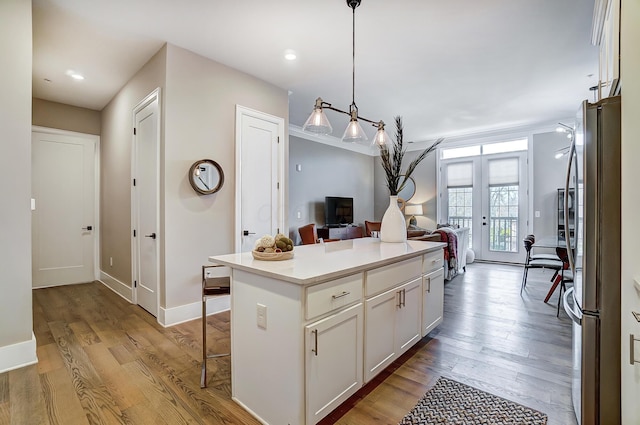 kitchen with stainless steel fridge, pendant lighting, light hardwood / wood-style flooring, a center island, and white cabinetry