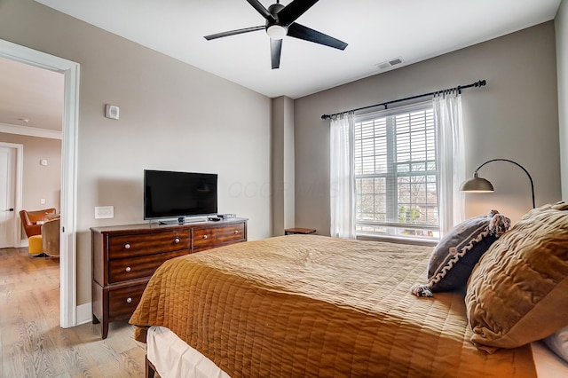 bedroom with ceiling fan, light hardwood / wood-style floors, and ornamental molding