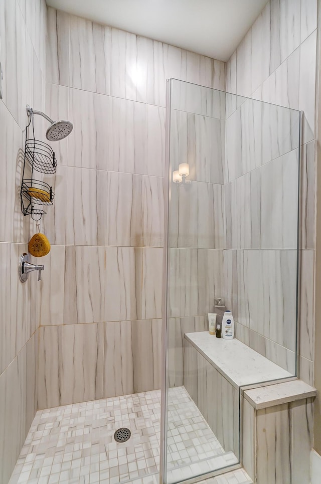 bathroom with a tile shower and tile walls