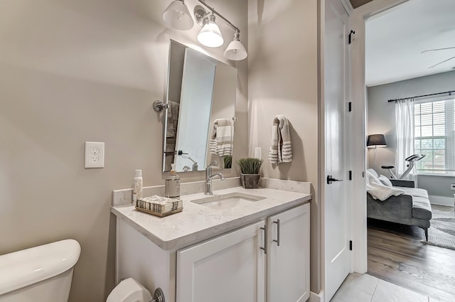 bathroom with hardwood / wood-style floors, vanity, toilet, and ceiling fan