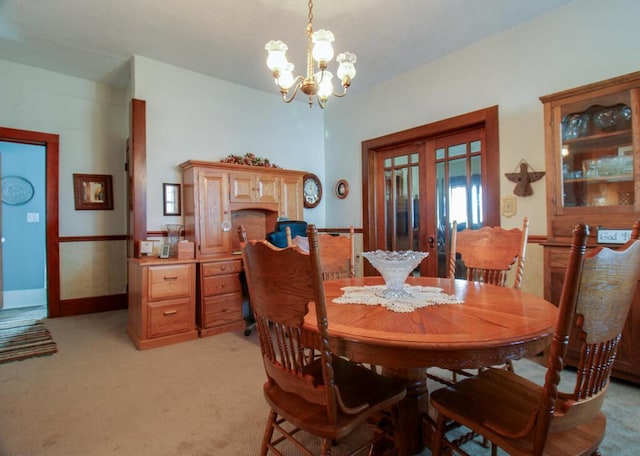 dining room with light carpet, french doors, and an inviting chandelier