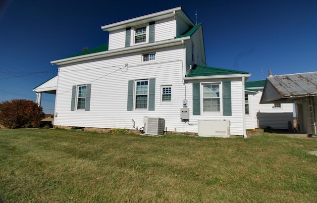 rear view of house with cooling unit and a yard