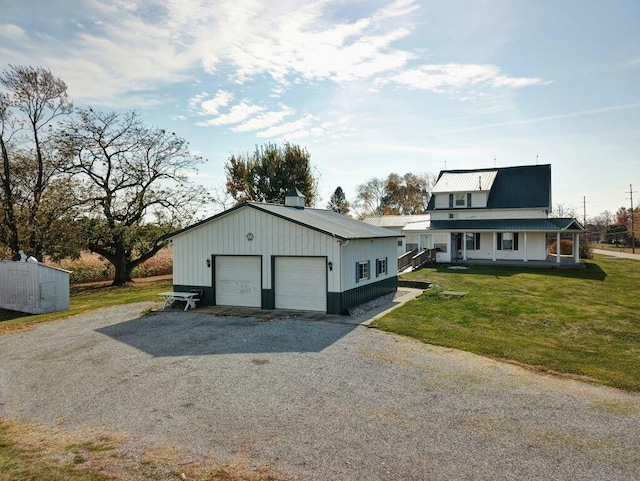 exterior space with covered porch, a garage, a front lawn, and an outdoor structure