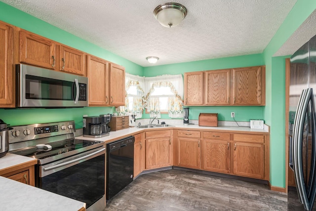 kitchen with a textured ceiling, sink, dark hardwood / wood-style floors, and appliances with stainless steel finishes