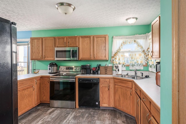 kitchen featuring black appliances, dark hardwood / wood-style floors, sink, and a textured ceiling