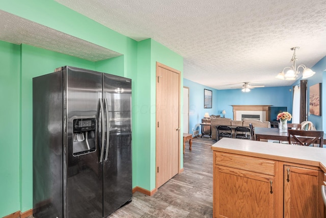 kitchen featuring stainless steel fridge with ice dispenser, hardwood / wood-style floors, hanging light fixtures, and a textured ceiling