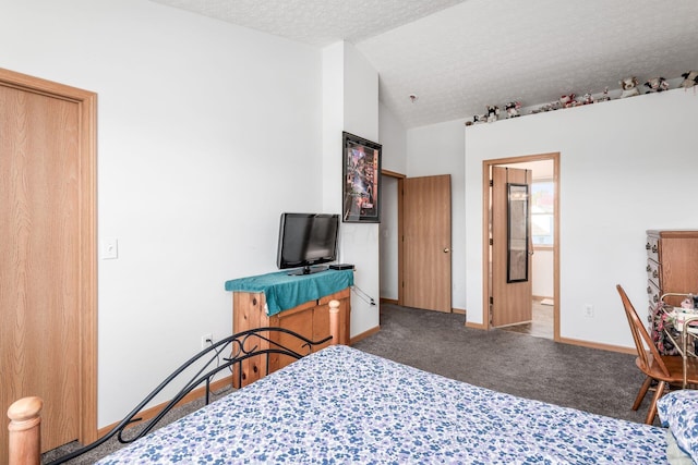 bedroom featuring a textured ceiling, connected bathroom, dark carpet, and vaulted ceiling