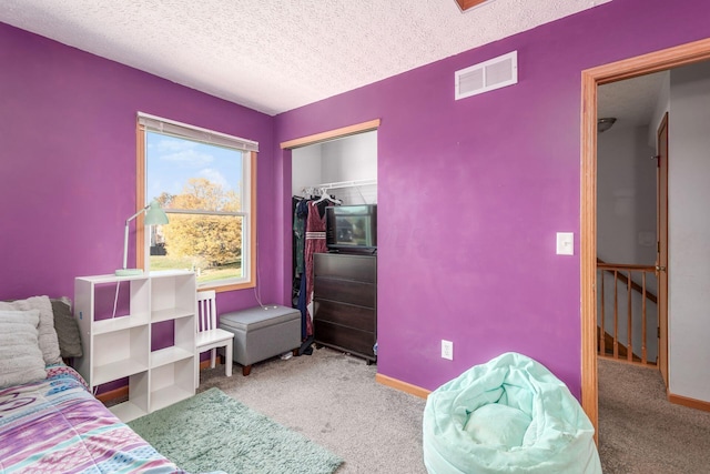 carpeted bedroom featuring a textured ceiling and a closet