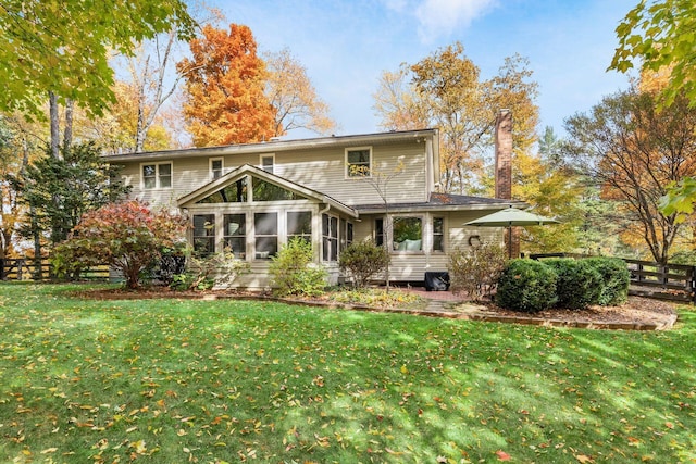 back of property with a sunroom and a yard