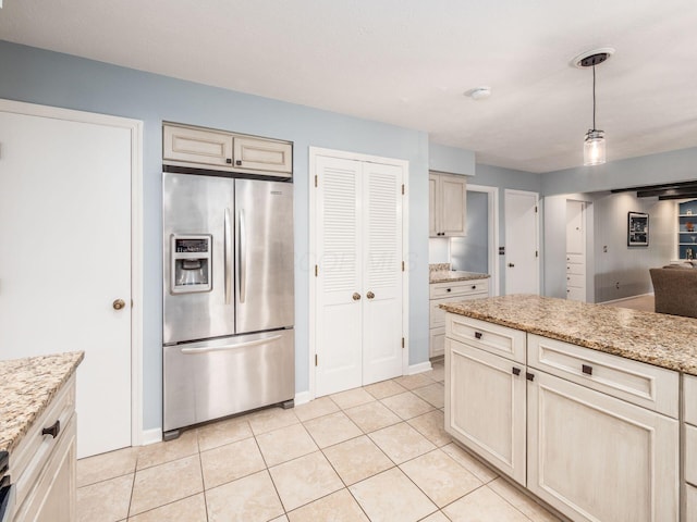 kitchen with pendant lighting, light stone counters, light tile patterned floors, and stainless steel refrigerator with ice dispenser