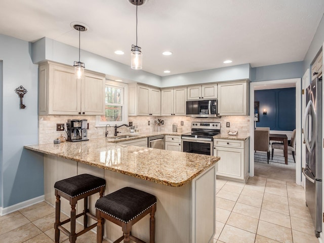 kitchen with pendant lighting, kitchen peninsula, sink, and appliances with stainless steel finishes