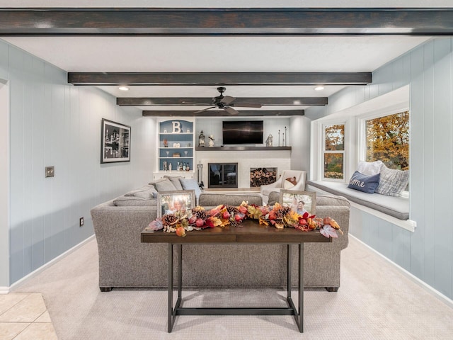 carpeted living room with beamed ceiling, ceiling fan, and wood walls