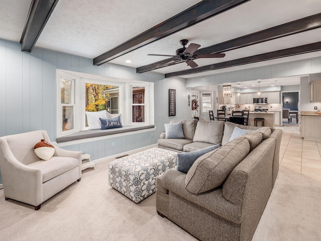 tiled living room featuring ceiling fan, beam ceiling, and a textured ceiling