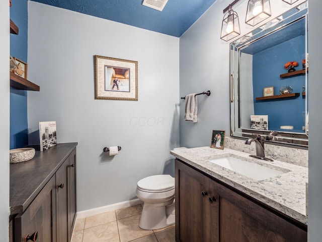 bathroom with tile patterned flooring, vanity, toilet, and a textured ceiling