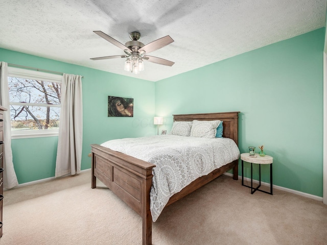 bedroom featuring ceiling fan, light colored carpet, and a textured ceiling