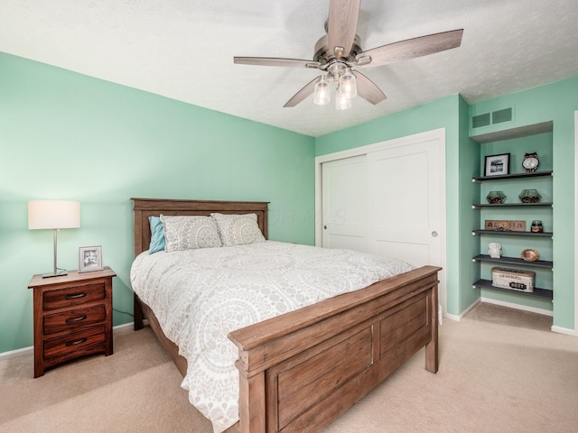 carpeted bedroom with a textured ceiling, a closet, and ceiling fan