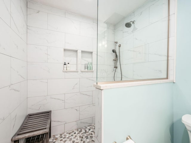 bathroom featuring toilet and a tile shower