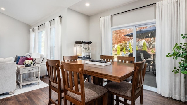 dining space featuring vaulted ceiling and dark wood-type flooring