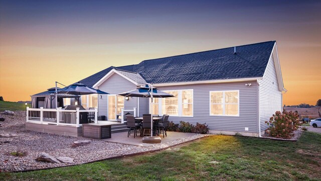 back house at dusk with a patio area and a yard