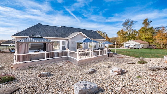 back of property with a gazebo, a wooden deck, and a lawn